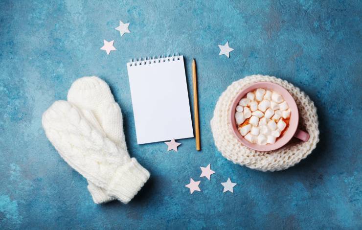 cup of hot chocolate with mittens and a notepad