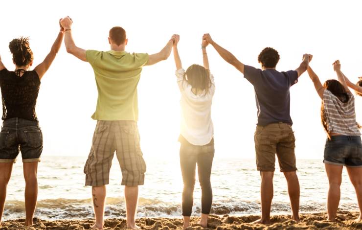 Volunteers standing on beach holding hands at sunset