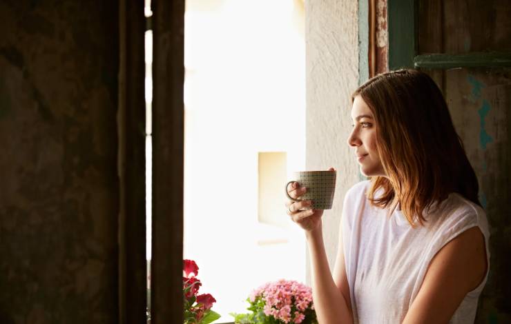 woman drinking coffee while looking out window