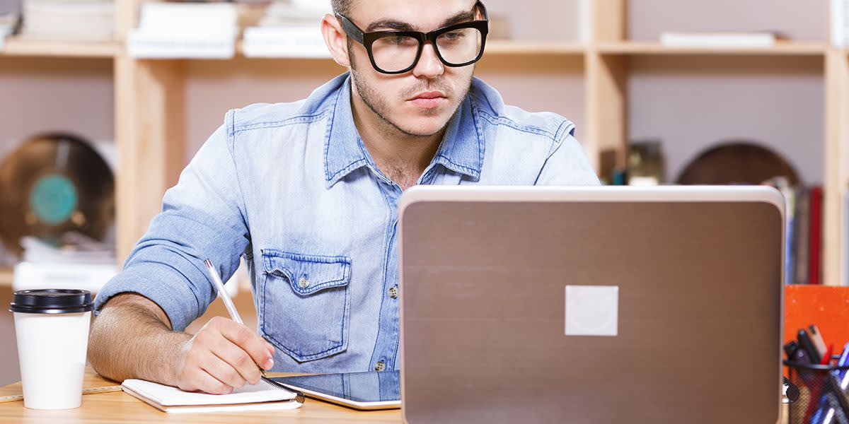 A young man looks at his laptop computer, checking email.