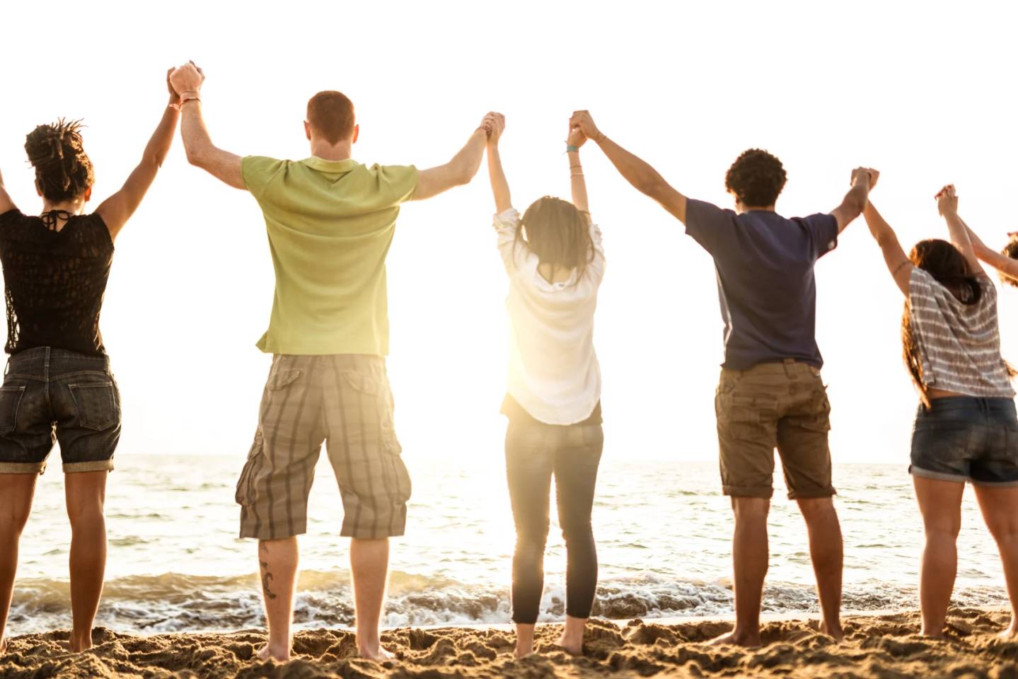 Volunteers standing on beach holding hands at sunset