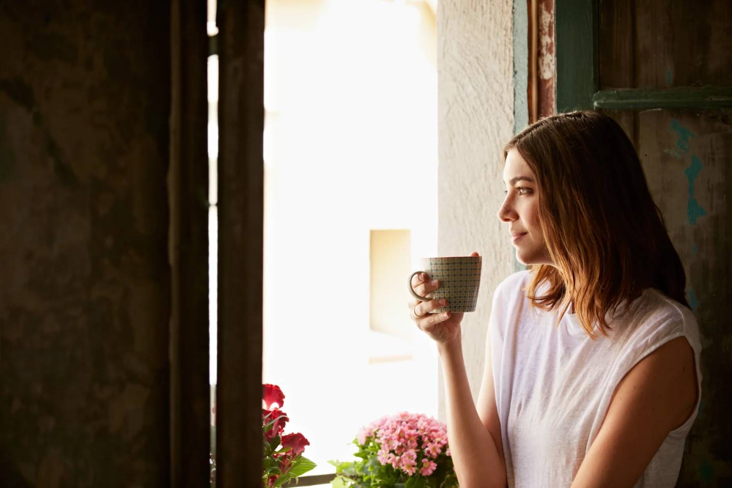 woman drinking coffee while looking out window