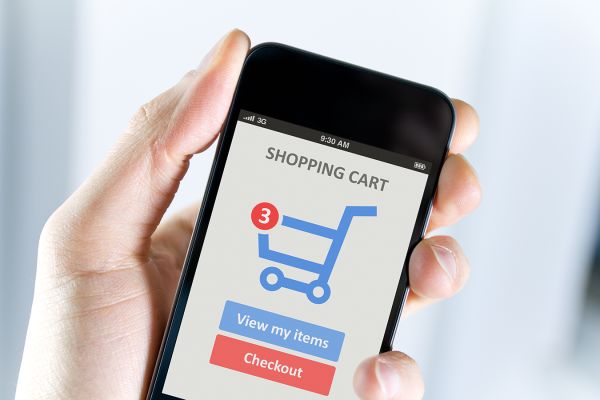 hand holding cell phone with shopping cart in screen